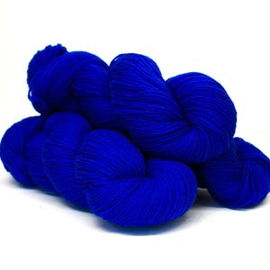 Puede incluir: Un ovillo de hilo azul vibrante, bien enrollado y listo para manualidades. El hilo es de un azul rico y saturado, con textura visible y un aspecto suave y acogedor. Perfecto para tejer, hacer ganchillo u otros proyectos de arte textil.