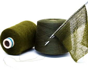 May include: Two spools of green yarn with a knitting needle and a piece of knitted fabric.