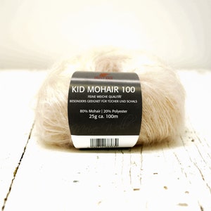 K&ouml;nnte beinhalten: Eine Kn&auml;uel Kid Mohair 100 Garn in einer hellbeigen Farbe. Das Etikett lautet "Kid Mohair 100", "Feine Weiche Qualitat", "Besonders Geeignet Fur Tucher Und Schals", "80% Mohair | 20% Polyester", "25g ca. 100m".