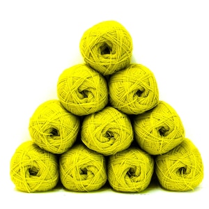 Puede incluir: Una disposición piramidal de diez ovillos de hilo de color amarillo chartreuse brillante. Cada ovillo está enrollado en forma esférica con hebras de fibra visibles. Los ovillos de hilo están apilados en formación triangular sobre un fondo blanco.