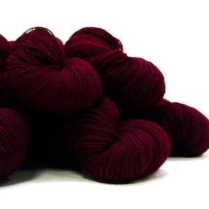 May include: A pile of deep burgundy yarn skeins. The yarn is soft and fluffy, perfect for knitting or crocheting.