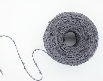 May include: A ball of gray yarn with a loose, textured weave. A length of yarn is unraveled from the ball.