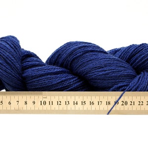 May include: A skein of dark blue yarn, measured with a ruler showing 27 centimeters.