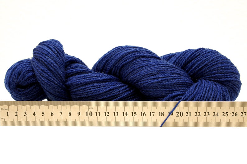 May include: A skein of dark blue yarn, measured with a ruler showing 27 centimeters.