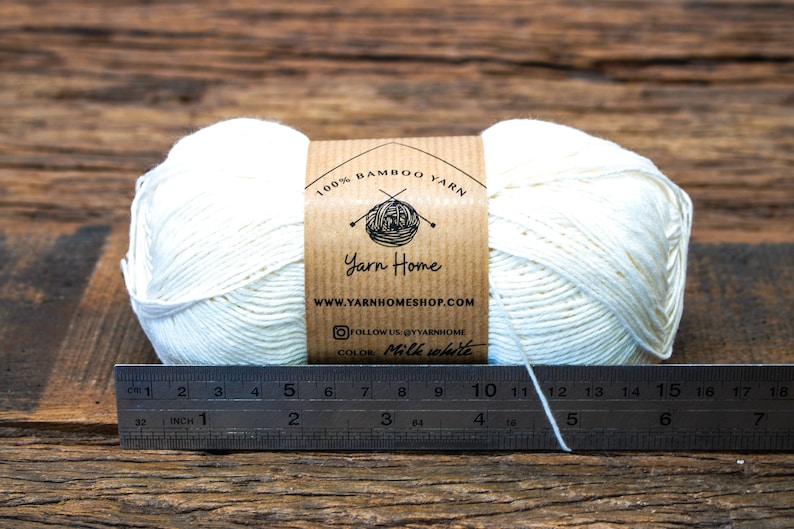 May include: A ball of 100% bamboo yarn in milk white color, with a brown label that says "Yarn Home" and "www.yarnhomeshop.com". The yarn is measured with a ruler in inches.