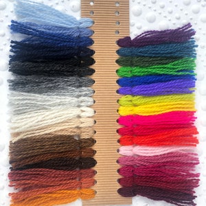 May include: A card with yarn samples in various colors, including blue, green, red, yellow, and purple. The yarn is arranged in rows on the card.