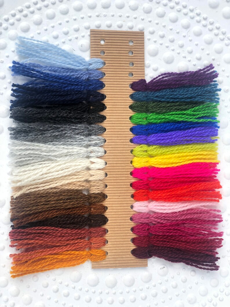 May include: A card with yarn samples in various colors, including blue, green, red, yellow, and purple. The yarn is arranged in rows on the card.