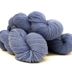 May include: Four skeins of blue yarn, arranged in a pile. The yarn is soft and fluffy, and it is perfect for knitting or crocheting.