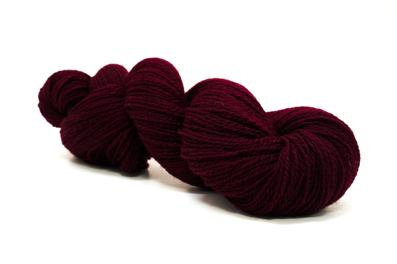 May include: A skein of deep burgundy yarn, wound into a heart shape, ready for knitting or crocheting.