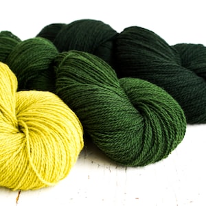 Puede incluir: Tres ovillos de lana, uno amarillo y dos verdes. La lana es suave y esponjosa, perfecta para tejer o hacer ganchillo.