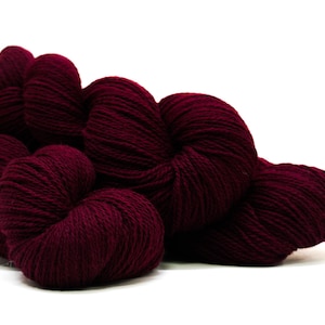 May include: A pile of deep burgundy yarn skeins, perfect for knitting or crocheting.