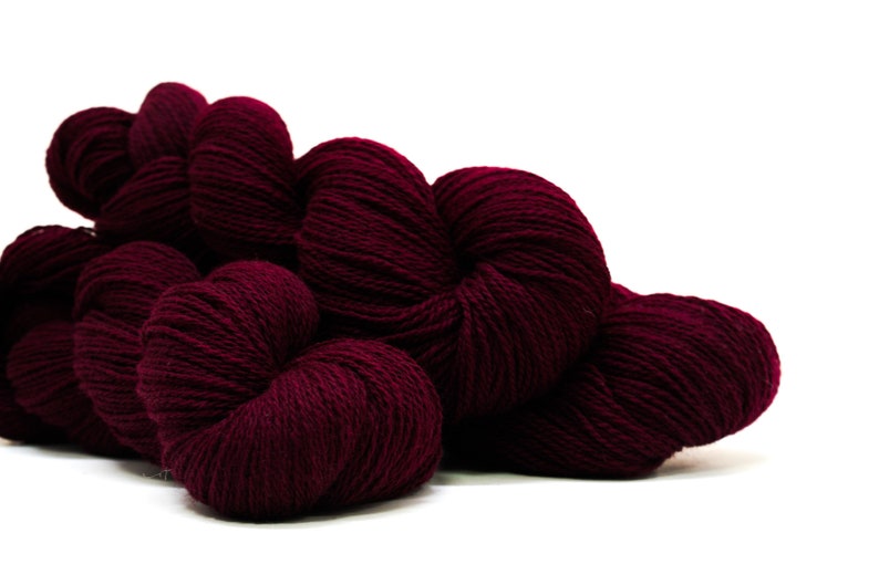 May include: A pile of deep burgundy yarn skeins, perfect for knitting or crocheting.