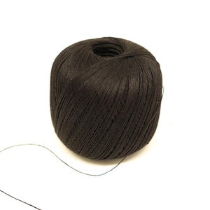 Pode incluir: Uma bobina de fio preto com um pequeno pedaço de fio que se estende da bobina.