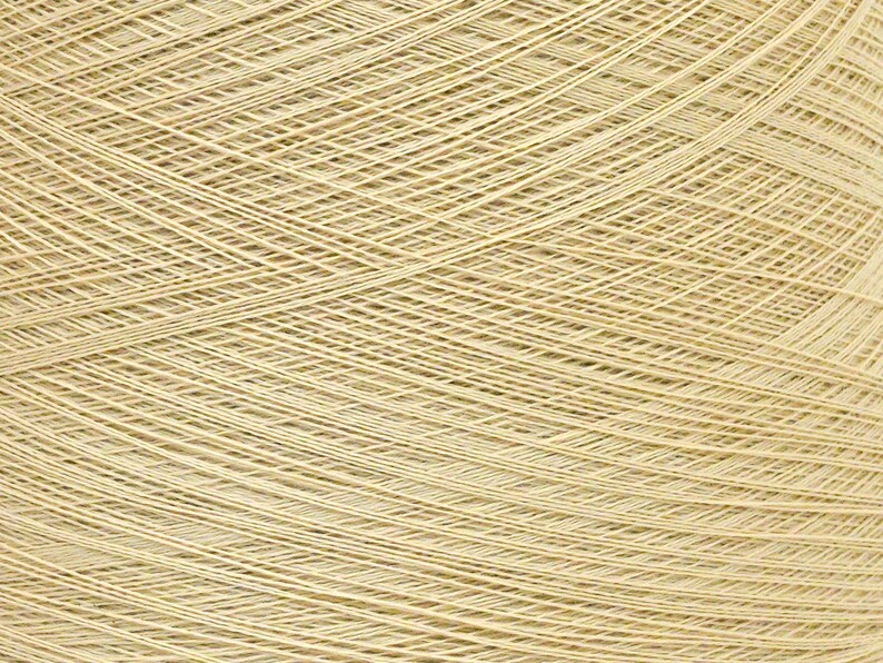 May include: Close-up of a large ball of beige yarn. The yarn is tightly wound, with visible diagonal and horizontal lines creating a textured surface. The yarn appears to be made of natural fibers, suitable for knitting or crocheting projects.