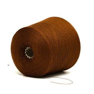 May include: A large spool of brown yarn, ideal for knitting or crocheting projects. The yarn is a rich, warm brown color and is tightly wound around a central core. The spool is set against a white background.