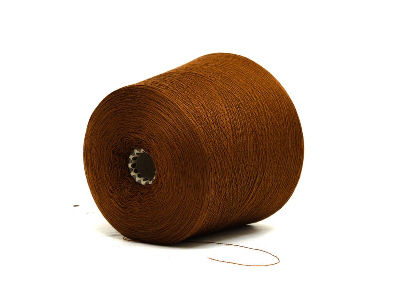 May include: A large spool of brown yarn, ideal for knitting or crocheting projects. The yarn is a rich, warm brown color and is tightly wound around a central core. The spool is set against a white background.