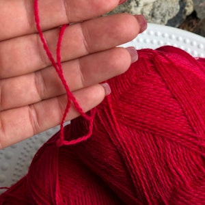 May include: A ball of bright red yarn with a single strand of yarn pulled out.