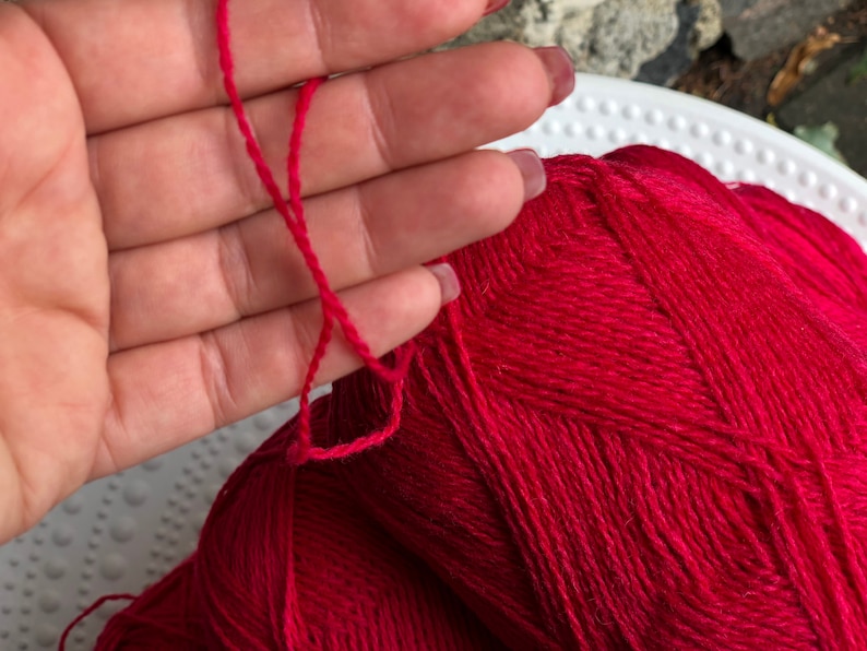 May include: A ball of bright red yarn with a single strand of yarn pulled out.