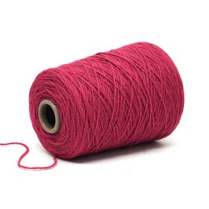 May include: A large spool of vibrant red yarn, ideal for knitting or crocheting projects. The yarn is tightly wound around a cardboard core, with a loose strand extending from the side. The background is plain white.