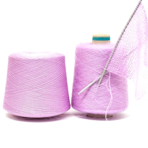 May include: Two spools of pale pink yarn, one with a crocheted piece of fabric attached to it. The fabric is attached to a knitting needle.