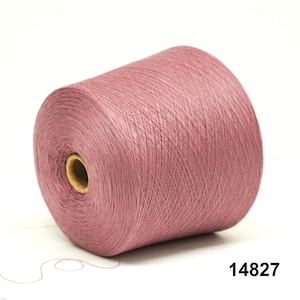 May include: A large spool of dusty rose-colored yarn. The yarn is tightly wound around a cardboard core. The number "14827" is printed in black on the lower right corner. The yarn is on a white background.