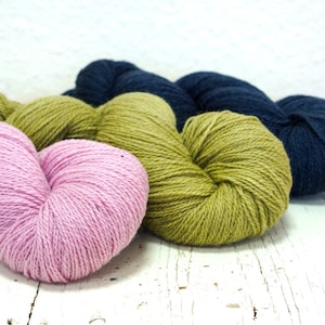 May include: Three skeins of yarn in pink, green, and blue. The yarn is soft and fluffy, and it is perfect for knitting or crocheting.