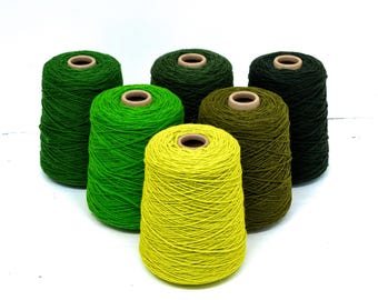 May include: Six spools of yarn in various shades of green and yellow. The yarn is wound around cardboard cores. The colors range from a bright lime green to a deep forest green, with a yellow-green spool in the foreground.