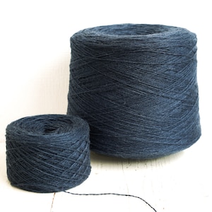Può includere: Due bobine di filo blu scuro, una più grande dell'altra. Il filo è avvolto stretto e ha una consistenza liscia.