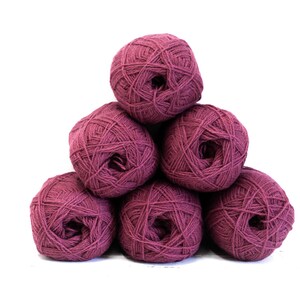 May include: A pyramid arrangement of six round balls of dark magenta yarn. Each ball features a textured, wound fiber construction with a visible center opening, showcasing a consistent deep reddish-purple color throughout the entire set of yarn.