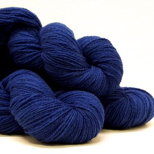 May include: Several skeins of deep blue yarn are piled together. The yarn is soft and fluffy, and it would be perfect for knitting or crocheting.