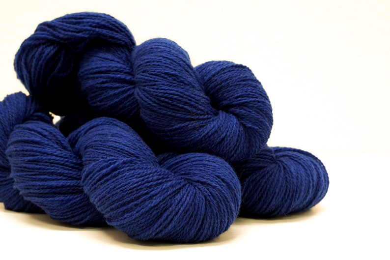 May include: Several skeins of deep blue yarn are piled together. The yarn is soft and fluffy, and it would be perfect for knitting or crocheting.