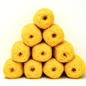 Könnte beinhalten: Ein pyramidenförmiger Stapel aus zehn runden Knäueln aus leuchtend gelbem Garn. Jedes Knäuel ist zu einer Kugel gewickelt und weist eine sichtbare Textur aus gedrehten Fasern auf. Das Garn ist einheitlich in Farbe und Größe.