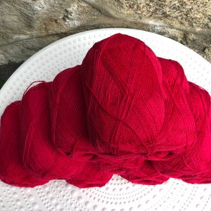 May include: A stack of six red yarn balls, likely for knitting or crocheting.