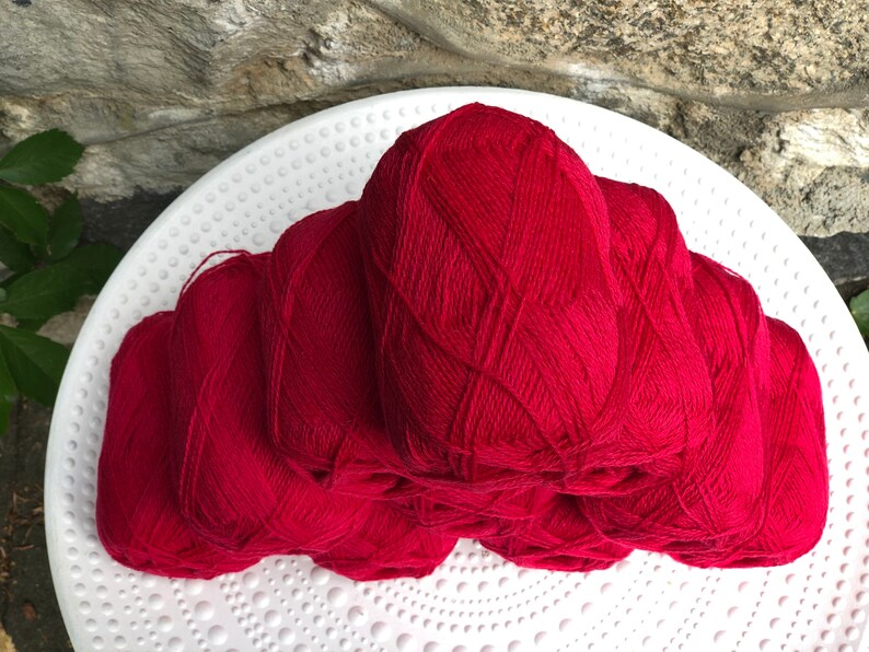 May include: A stack of six red yarn balls, likely for knitting or crocheting.