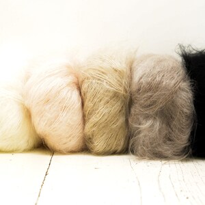 K&ouml;nnte beinhalten: F&uuml;nf Kn&auml;uel Garn in verschiedenen Farbt&ouml;nen von Beige, Braun und Schwarz. Das Garn ist weich und flauschig und perfekt zum Stricken oder H&auml;keln.