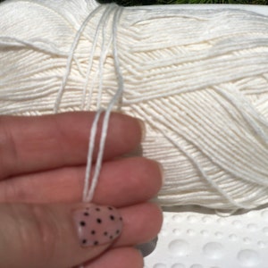 May include: A ball of white yarn with a long strand of yarn hanging from it.