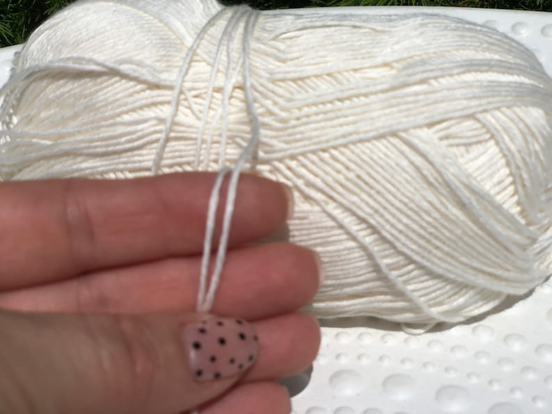 May include: A ball of white yarn with a long strand of yarn hanging from it.