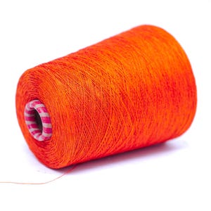 Könnte beinhalten: Eine leuchtend orangefarbene Garnrolle, ideal für Näh- und Bastelprojekte. Der Faden ist eng um einen Pappkern mit rosa und weißen Streifen gewickelt. Die leuchtende Farbe eignet sich für verschiedene Textilanwendungen.