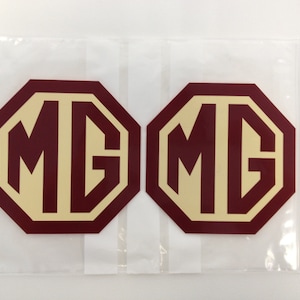 May include: Two burgundy octagonal stickers with a white MG logo in the centre. The stickers are packaged in a clear plastic bag.
