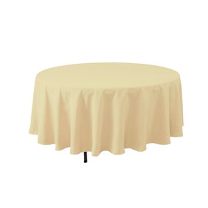 May include: A round, cream-colored tablecloth with a smooth, even texture. The tablecloth is draped over a table and has a slight drape.