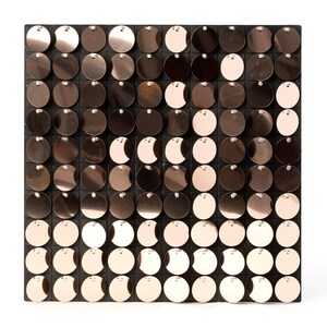 May include: A square-shaped decorative wall panel with a grid of round, metallic, rose gold sequins. The sequins are arranged in a gradient pattern, with darker sequins at the top and lighter sequins at the bottom.