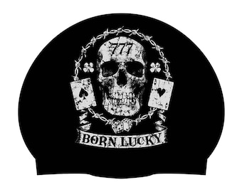 May include: Black swim cap with a white skull and crossbones design. The skull has the number 777 on its forehead. The design also includes playing cards and dice. The text "Born Lucky" is printed below the skull.