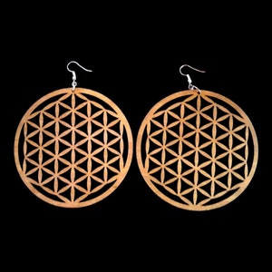 May include: A pair of large, round wooden earrings with a geometric flower of life design. The earrings are brown and have silver hooks.
