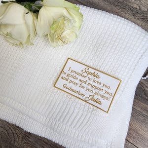 May include: White knitted baby blanket with a gold embroidered tag that reads "I promise to love you, Sophia, to guide and support you, and pray for you always! Godmother Julia"