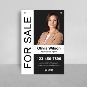 May include: A rectangular real estate sign featuring the text FOR SALE in large vertical letters. It displays a photograph of a person in a tan blazer, the name Olivia Wilson, the title Real Estate Agent, phone number 123-456-7890, and email.