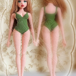 May include: A crocheted doll with long curly hair wearing a green swimsuit. The doll is standing on a floral patterned background.