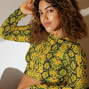 Pode incluir: Um top curto de manga comprida amarelo e verde com padrão de pele de cobra.