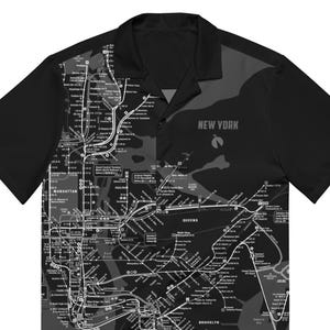 Puede incluir: Camisa negra de manga corta con cuello de campamento, que muestra un mapa detallado del metro de la ciudad de Nueva York en gris y blanco. El texto "NEW YORK" está impreso en la parte superior derecha.