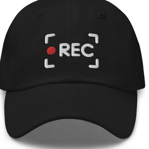 May include: Black baseball cap with a white embroidered recording symbol and the word "REC" in white.