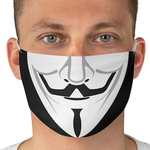 May include: A black face mask with a white stylized image of a smiling face with a mustache and goatee. The mask is worn by a person with short brown hair.